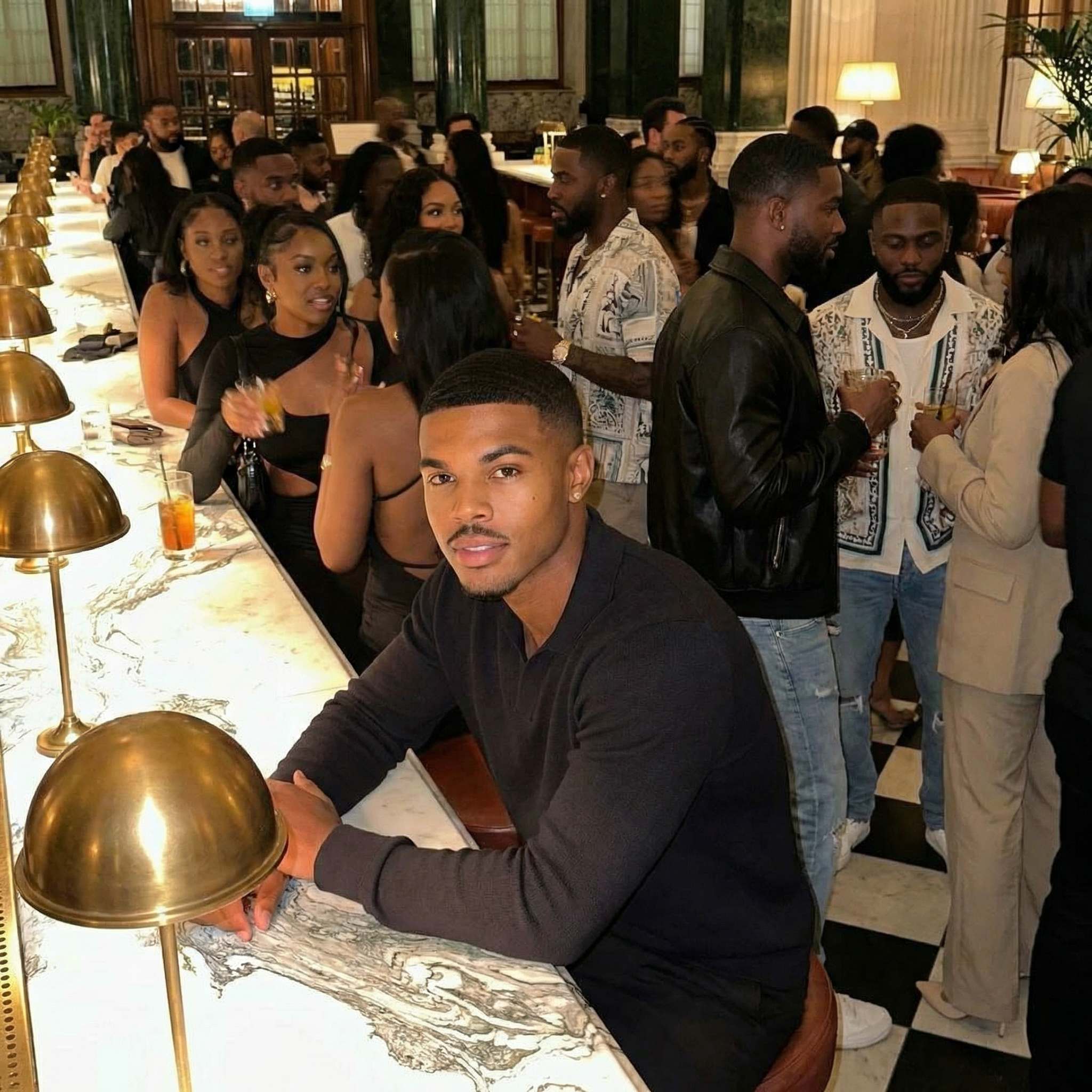 Man at marble bar with brass lamps in crowded venue